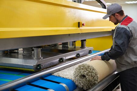 Laundry worker in the process of working on automatic machine for carpet washing in dry cleaningの写真素材