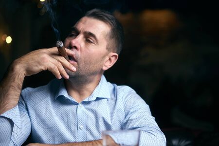 portrait of hansome man smoking cigar in a lounge barの写真素材