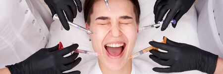 Conceptual beauty and cosmetology image of hands of several doctors holding syringes. Beauty and Cosmetology concept. Cosmetic procedures mesotherapyの写真素材