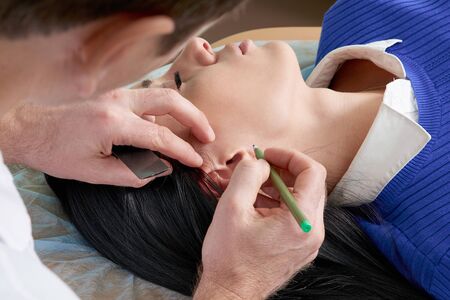 Plastic surgeon examines ear of patient before plastic surgeryの写真素材