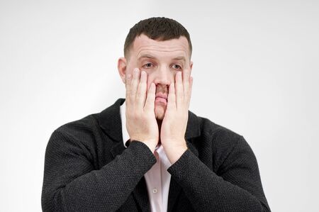 Stressed businessman with hands on the face over grey background with copy space, sadness and...