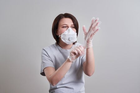 Young woman wearing face mask for protection from corona virus over grey background with copy spaceの写真素材
