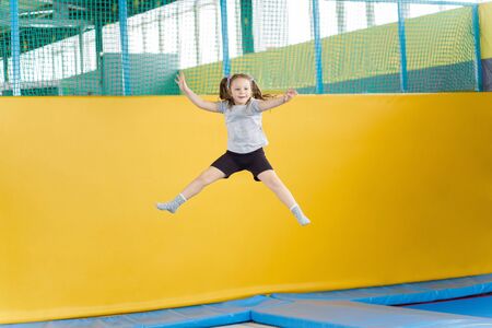 Happy little girl jumping on trampoline in fitness centerの写真素材