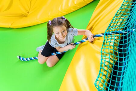 Girl playing in trampoline center jumping and climbing with ropeの写真素材