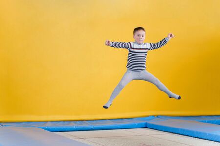 Happy smiling small kids jumping on indoors trampoline in entertainment center