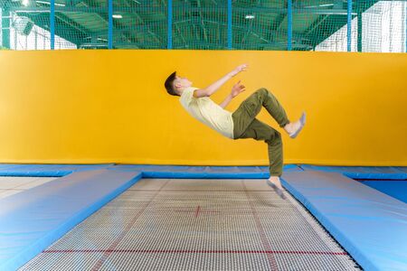Teenage boy jumping on trampoline park in sport centerの写真素材