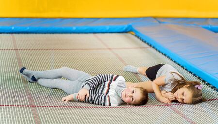 Happy smiling small kids laying on indoor trampoline in entertainment centerの写真素材