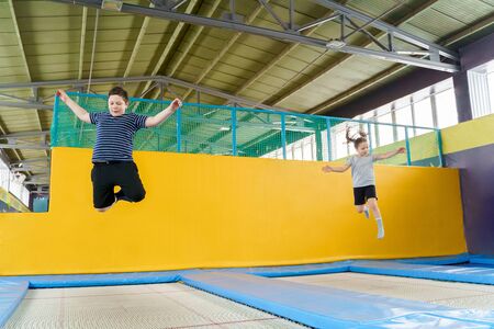 Happy smiling small kids jumping on indoors trampoline in entertainment centerの写真素材