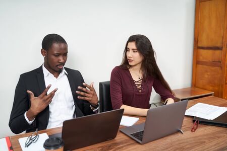 Young happy business people working together in modern office, multiethnic teamwork. Man calling...