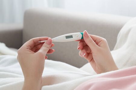 Woman holding a digital thermometer. Concept of fever, flue, virus and quarantine