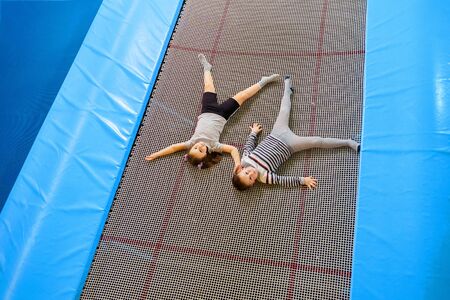 Happy smiling small kids laying on indoor trampoline in entertainment centerの写真素材