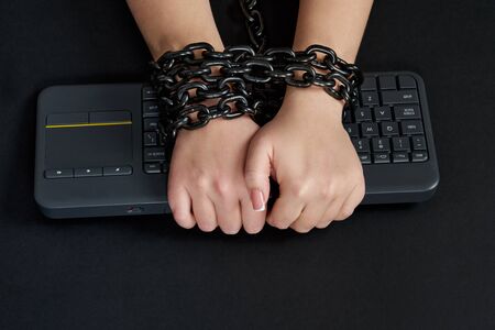 Female hands Chained to black Keyboard, addiction concept