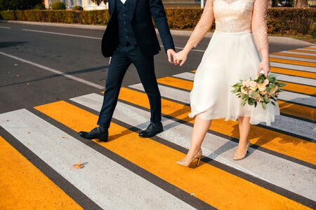 A happy couple crosses the road at a bright yellow pedestrian crossingの写真素材