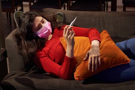 young woman holding thermometer on sofa got fever, caught, sick girl having influenza symptoms, flu...