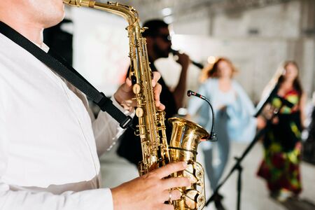 Concert view of a saxophone player with vocalist and musical jazz band in the backgroundの写真素材