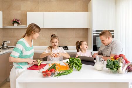 Smiling Family Dining Together at kitchen table and having fun, parents with two daughters