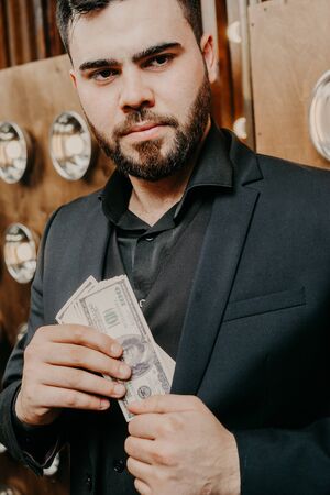 Young man with beard Putting dollars Money In His Pocketの写真素材