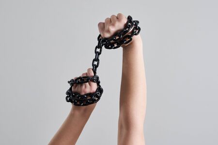 Female hands holding metal metal chain over headの写真素材