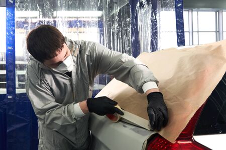 Mechanic covering car with paper before painting in auto repair serviceの写真素材