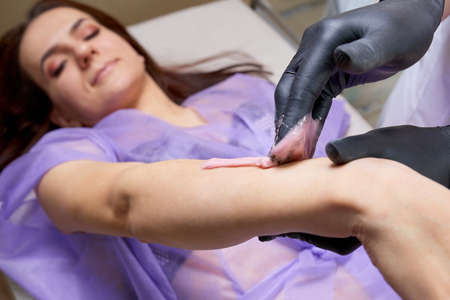 Waxing in beauty salon by professional. Beauty salon worker applying wax and tape to remove hair...