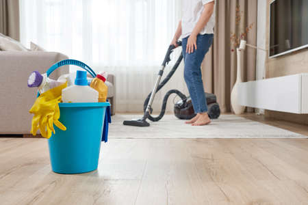 Woman cleaning the carpet with vacuum cleaner in the living roomの写真素材