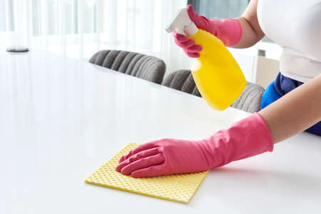 Cleaning home table sanitizing kitchen table surface with disinfectant spray bottle washing surfaces...