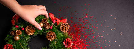 Female hands holding christmas wreath over black background with glitter and copy spaceの写真素材
