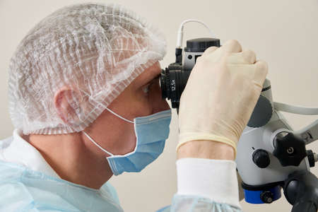 Dentist working with dental microscope and patient at modern dentist clinic