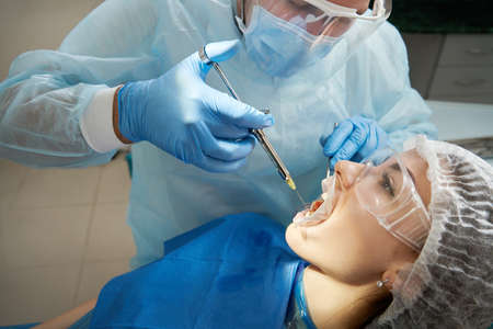 Dentist making local anesthesia shot before surgery. Patient visiting a dental office