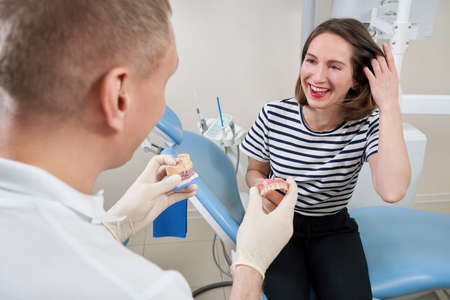 Male dentist showing his female patient a dental implant