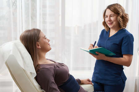 doctor is talking with young female patient and making notes while standing nearの写真素材