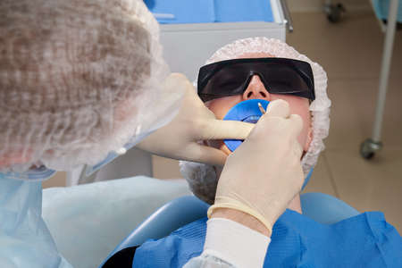 Dentist doing a dental treatment on a female patient. Dentist examining a patients teeth in modern dentistry officeの写真素材