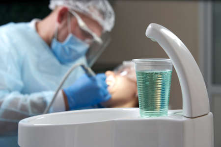 Dentist doing a dental treatment on a female patient. Dentist examining a patients teeth in modern dentistry officeの写真素材