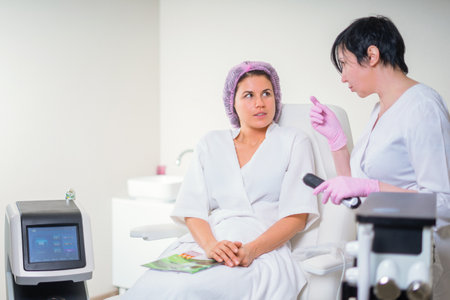 woman in a beauty salon discuss anti-aging treatment with cosmetologist looking through magazineの写真素材