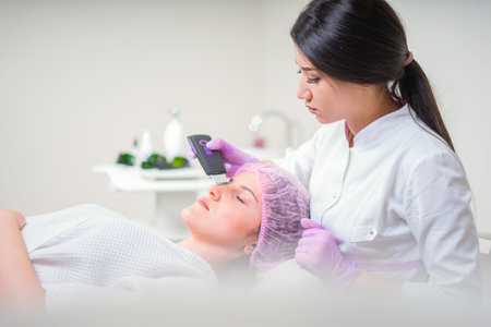 Hands of cosmetologist making ultrasound facial cleaning with special machineの写真素材