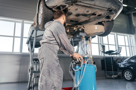 Car Mechanic Replacing Oil in Motor Engine. Auto service shopの写真素材
