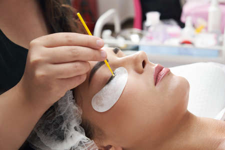 Eyelash extension procedure close up. Beautiful Woman with long lashes in a beauty salon