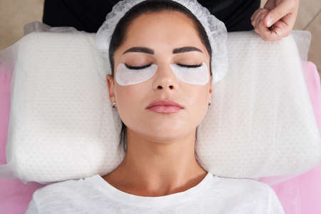 Beautiful Woman with long lashes in a beauty salon. Eyelash extension procedure