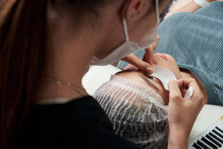 Eyelash extension procedure close up. Beautiful Woman with long lashes in a beauty salon