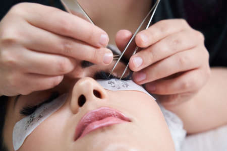 Eyelash extension procedure with tweezers in beauty salonの写真素材