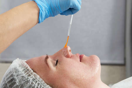 cosmetologist applies oil to the client face in the beauty salonの写真素材