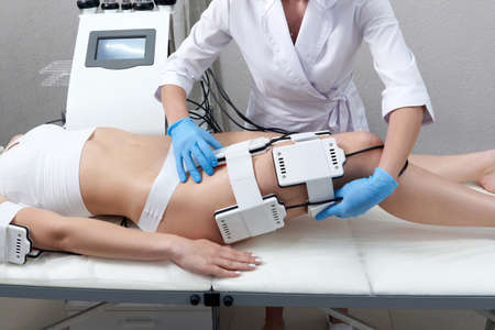 Beautiful woman getting electro stimulation therapy. Laser lipo equipment. Cosmetic fat reduce...