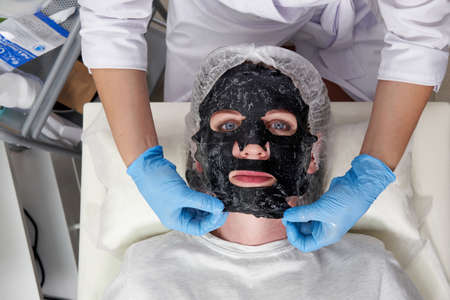 young woman with a black oxygen bubble mask on her face in beauty salonの写真素材