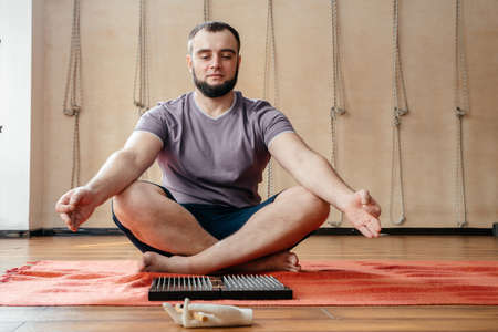 Man sitting in lotus pose in yoga studio meditatingの写真素材
