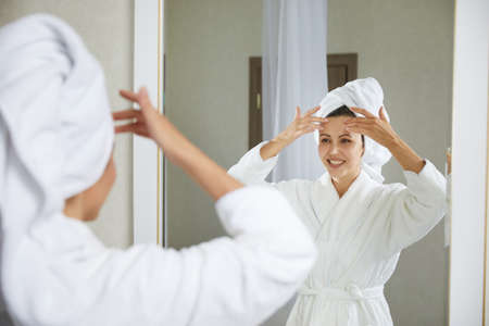 Young girl doing facial gymnastics self massage and rejuvenating exercises in the morning after...