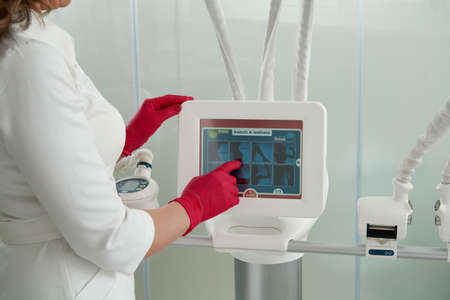 Cropped view of cosmetologist operating modern cosmetology equipment beauty clinic. Modern beauty...