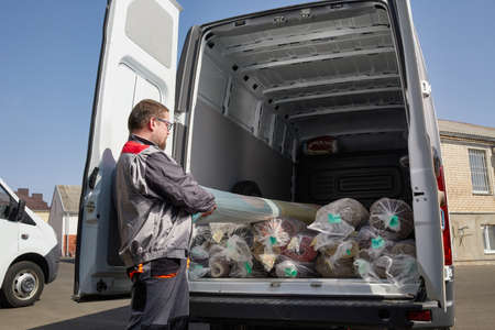 Worker standing near truck full of carpets. Cleaning service concept