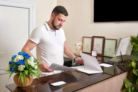 Man at office reception desk working with papers