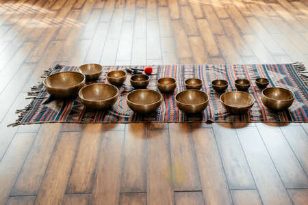 Many Tibetan handcrafted singing bowls on the floor in yoga class, sound therapy concept