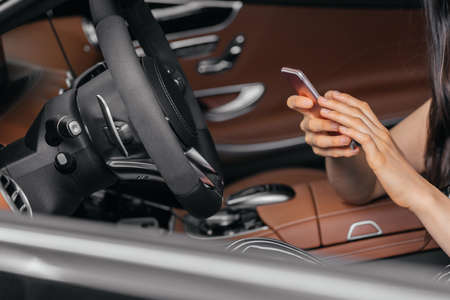 Young attractive asian woman using phone while sitting in a luxury car front sea